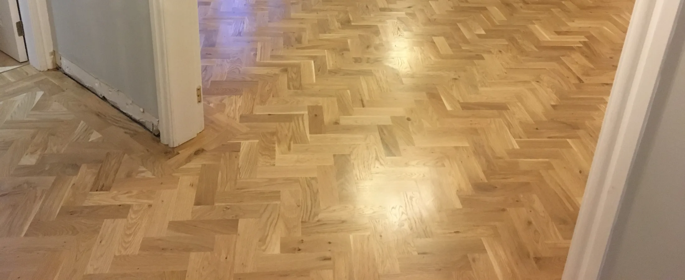 Parquet floor part way through being sanded back to bare wood
