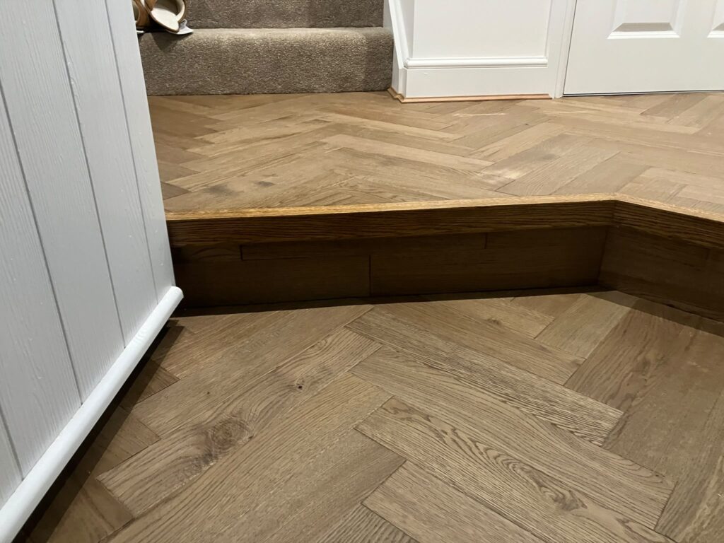 Oak herringbone floor stepping down, with a matching oak nosing and riser