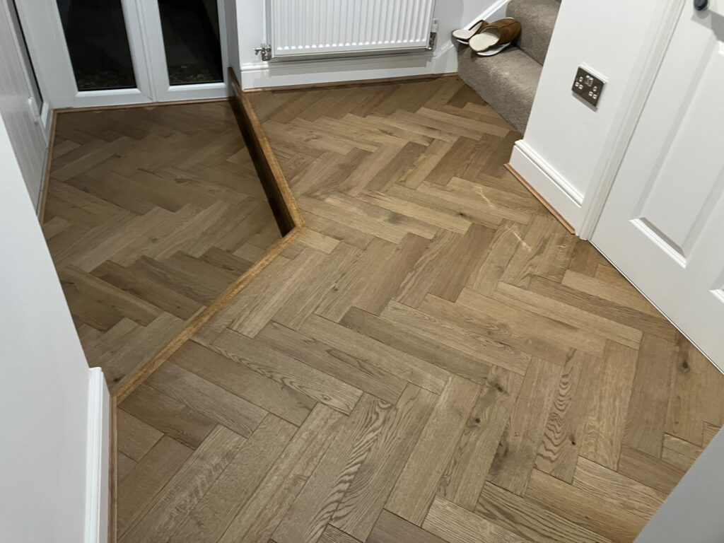 Ted Todd Husk oak herringbone in a hallway at the foot of the stairs, with an oak-edged step